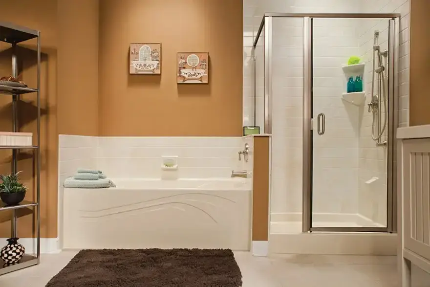 Modern bathroom remodel showcasing a white alcove soaking bathtub with an organic wave apron design next to a walk-in shower with a chrome frame glass door, set against warm ochre walls.