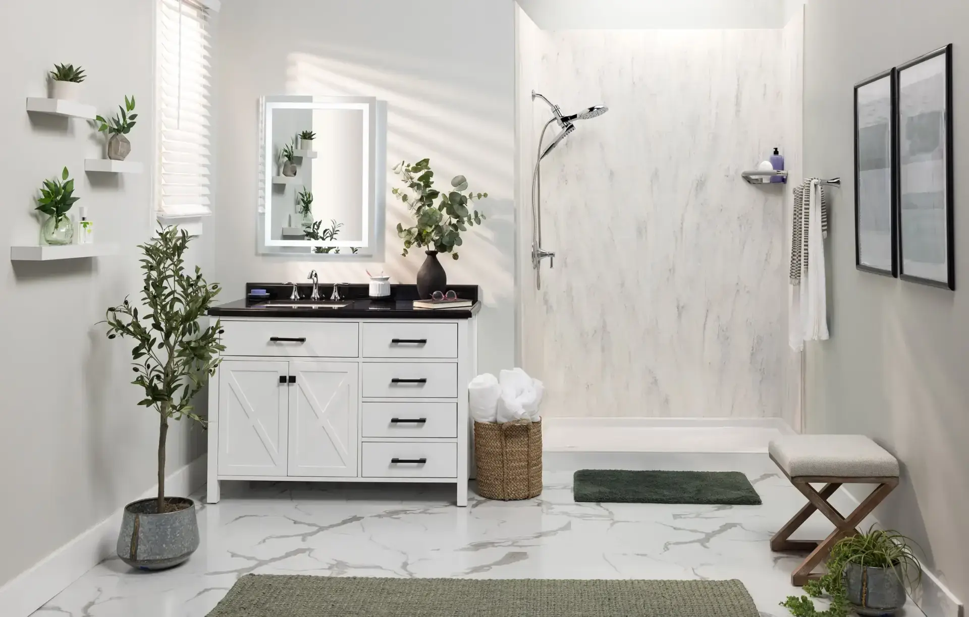 Bright master bathroom featuring a white single vanity with an X-brace farmhouse design and black countertop, an illuminated rectangular mirror, and an open doorless walk-in shower on marble tile flooring.
